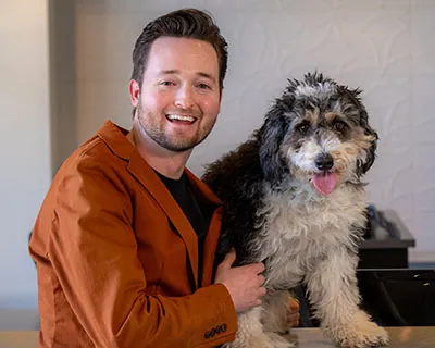 Dr. Moody sitting with the office support dog at uptown family dental. 